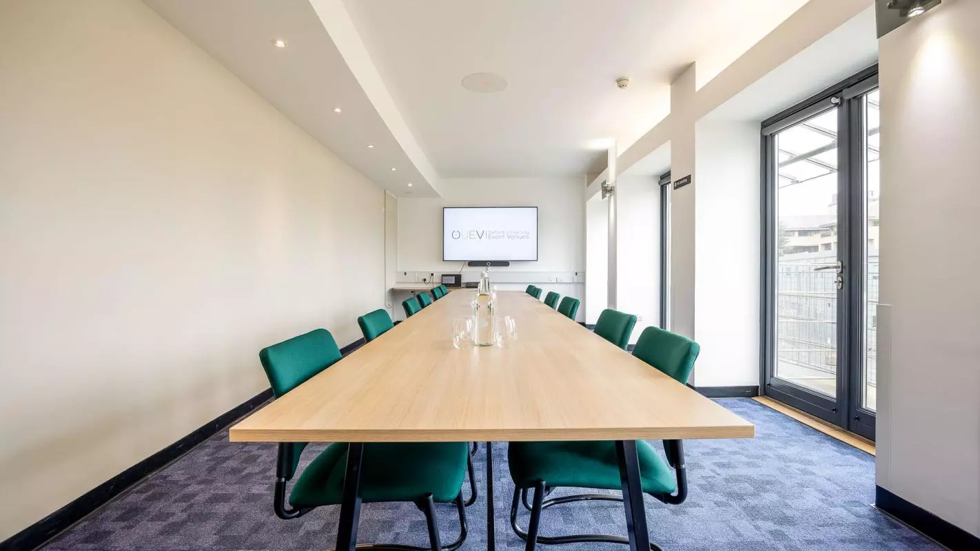 Long rectangular table with green chairs around the outside 