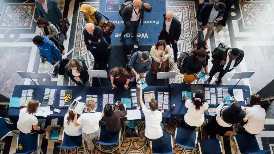Image shows foyer of Exam Schools with delegates arriving to the reception desk to find their name badge