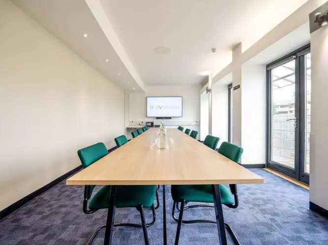 Long rectangular table with green chairs around the outside 