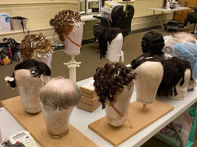 wigs sat on mannequin heads on a long trestle table in Exam Schools.