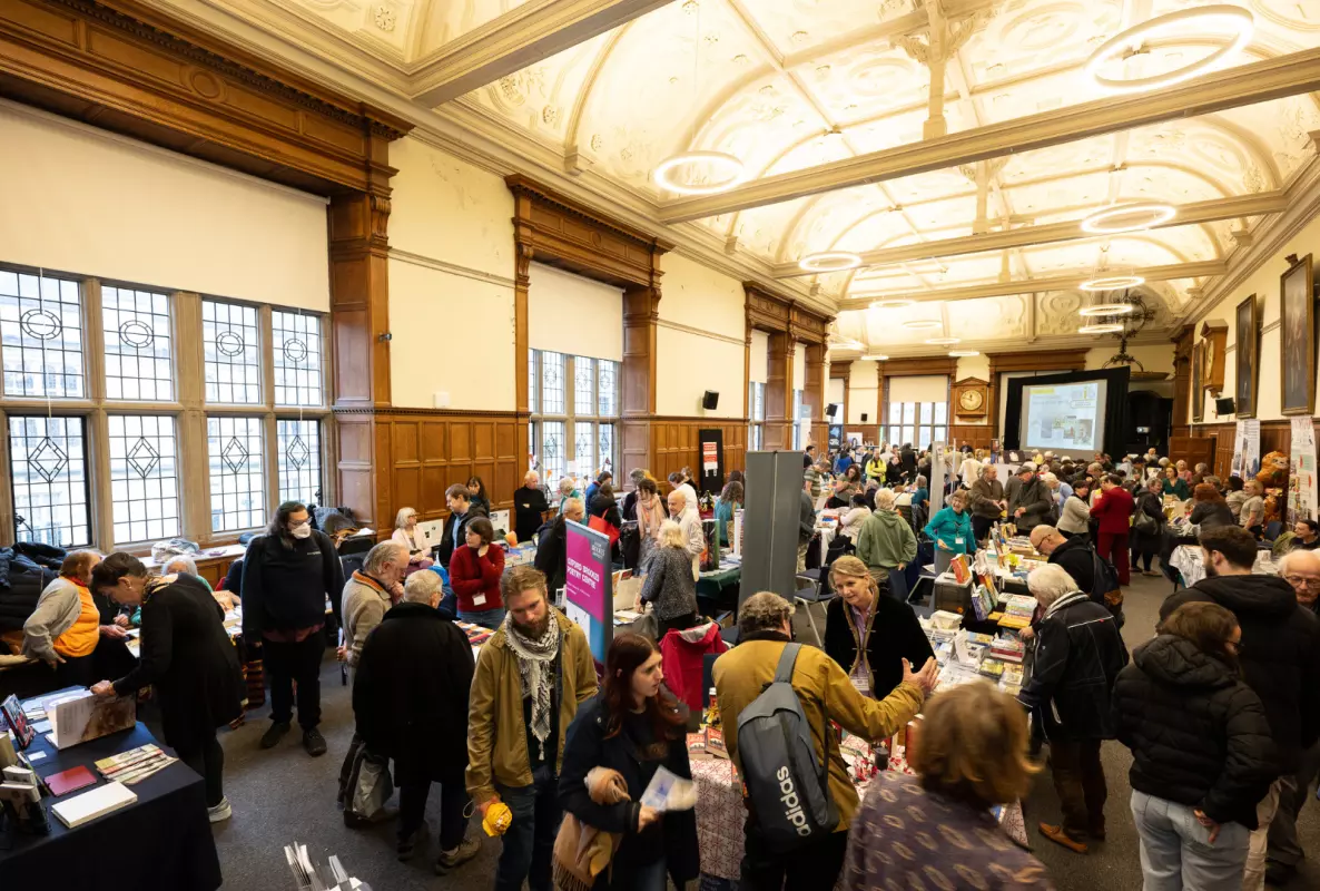 people walking around a fair at Exam Schools, looking at a variety of stalls and having conversations with staff.