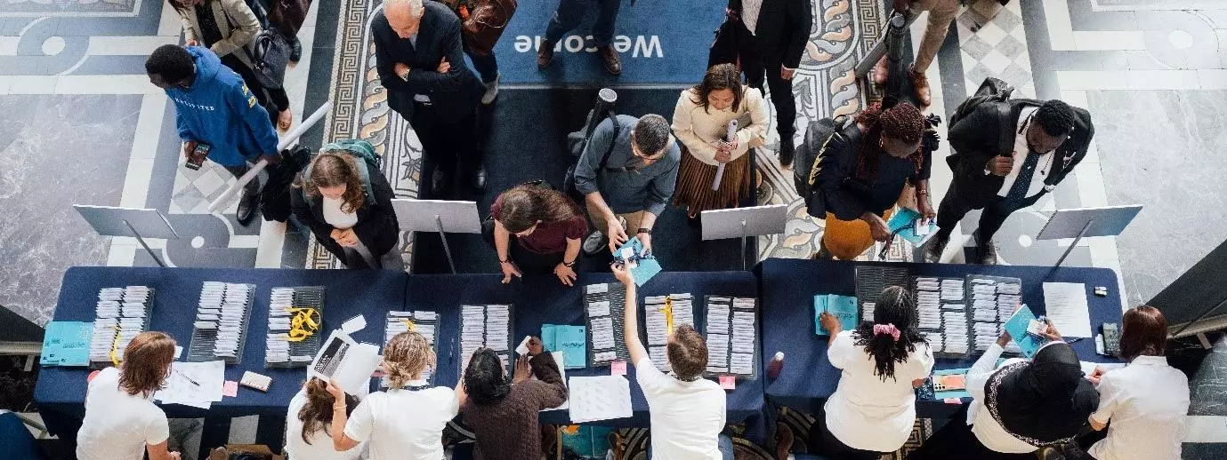 Image shows foyer of Exam Schools with delegates arriving to the reception desk to find their name badge